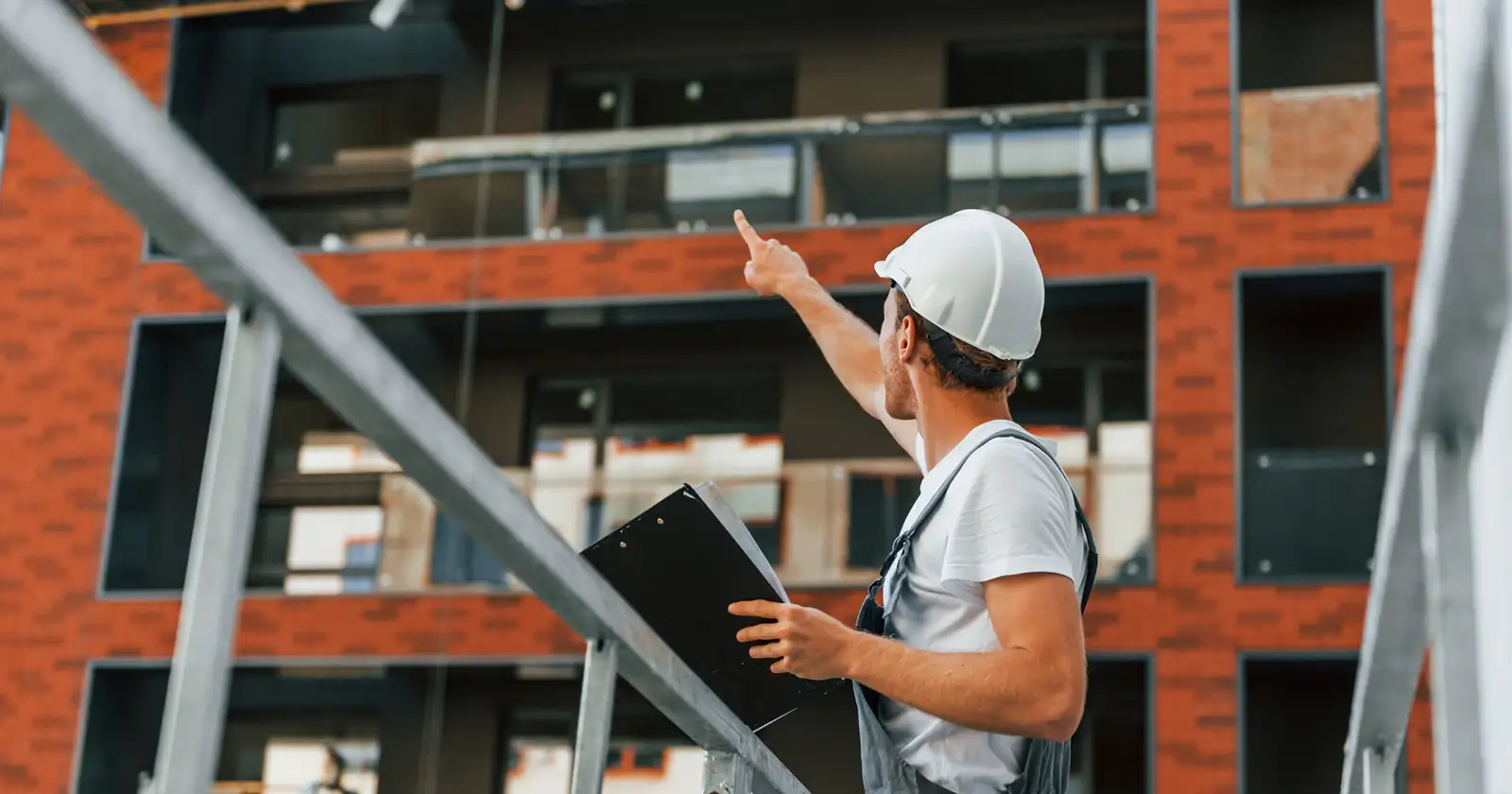 Manager of project. Young man working in uniform at construction at daytime.