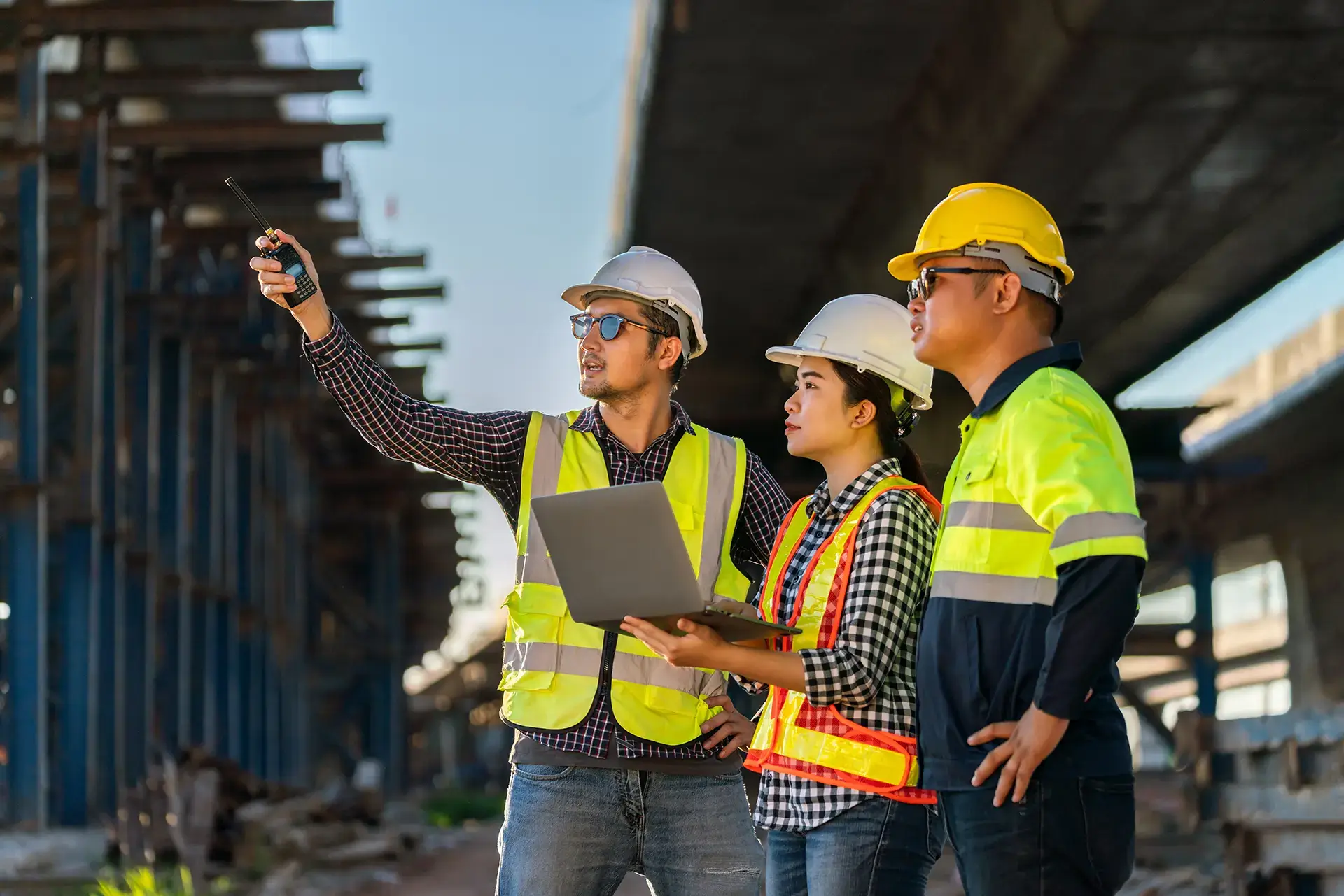 team of workers looking at something while holding a laptop