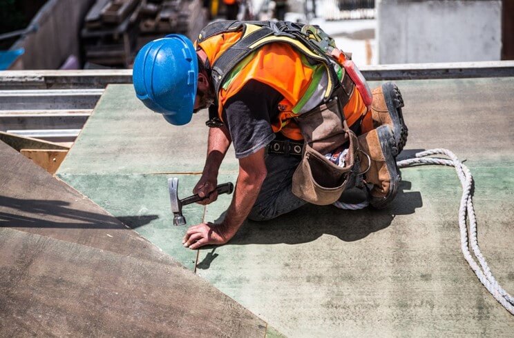 construction worker in a hard hat hammering a nail