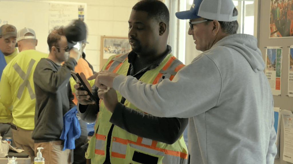 customer support representative showing a worker how to use the app