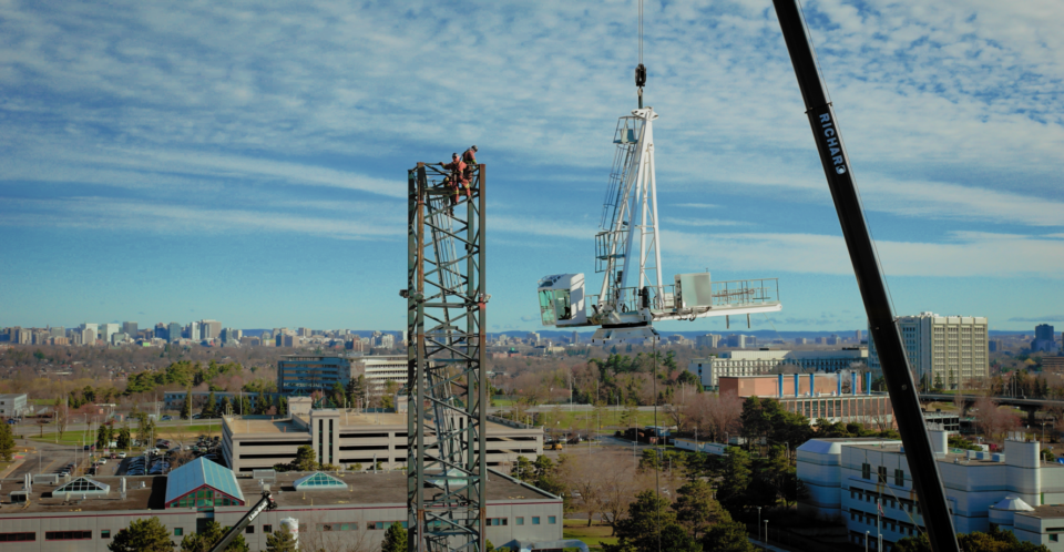 a tower crane slewing unit hanging from a mobile crane before installation